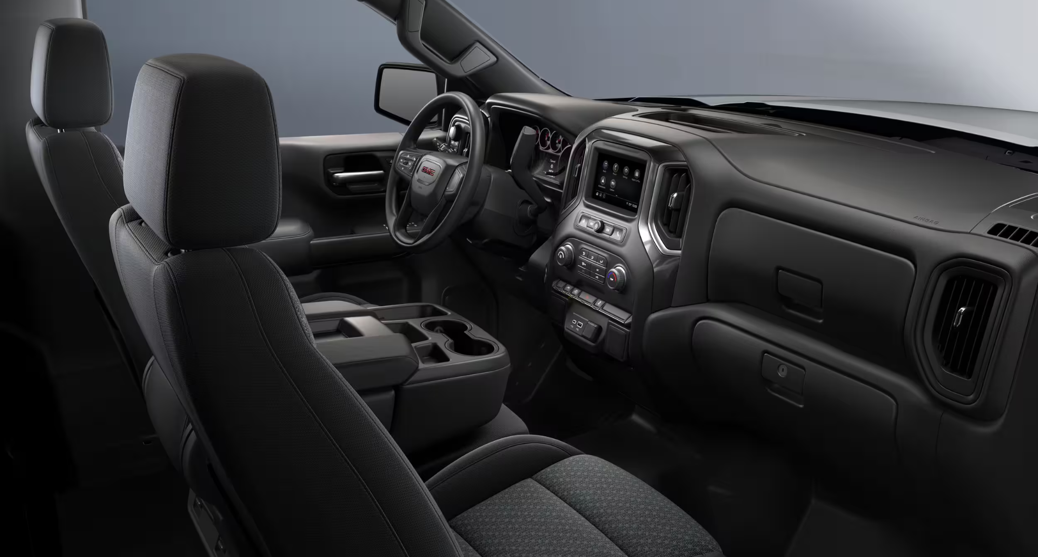 Interior seating view of the 2025 GMC Sierra 1500 Pro 4x4 showing durable cloth seats, center console with cupholders, and driver-focused dash.