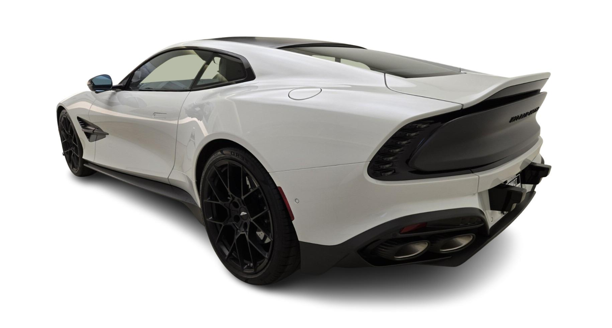 Rear angle of a 2025 Aston Martin Vanquish Coupe showcasing quad exhaust tips, carbon fiber rear fascia, and sculpted body lines.