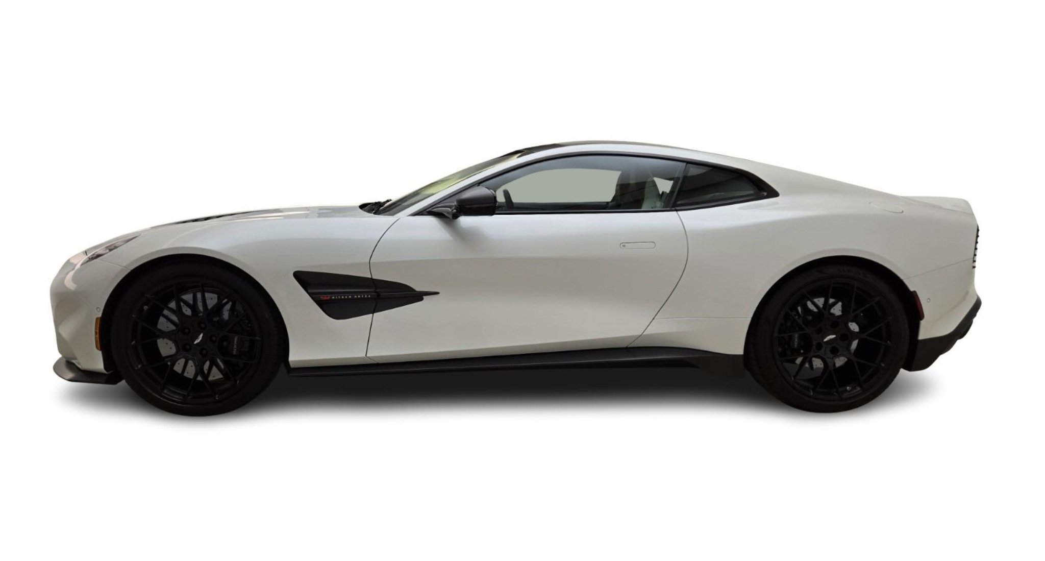 Side profile of the 2025 Aston Martin Vanquish Coupe in white with black forged wheels and aerodynamic carbon accents.