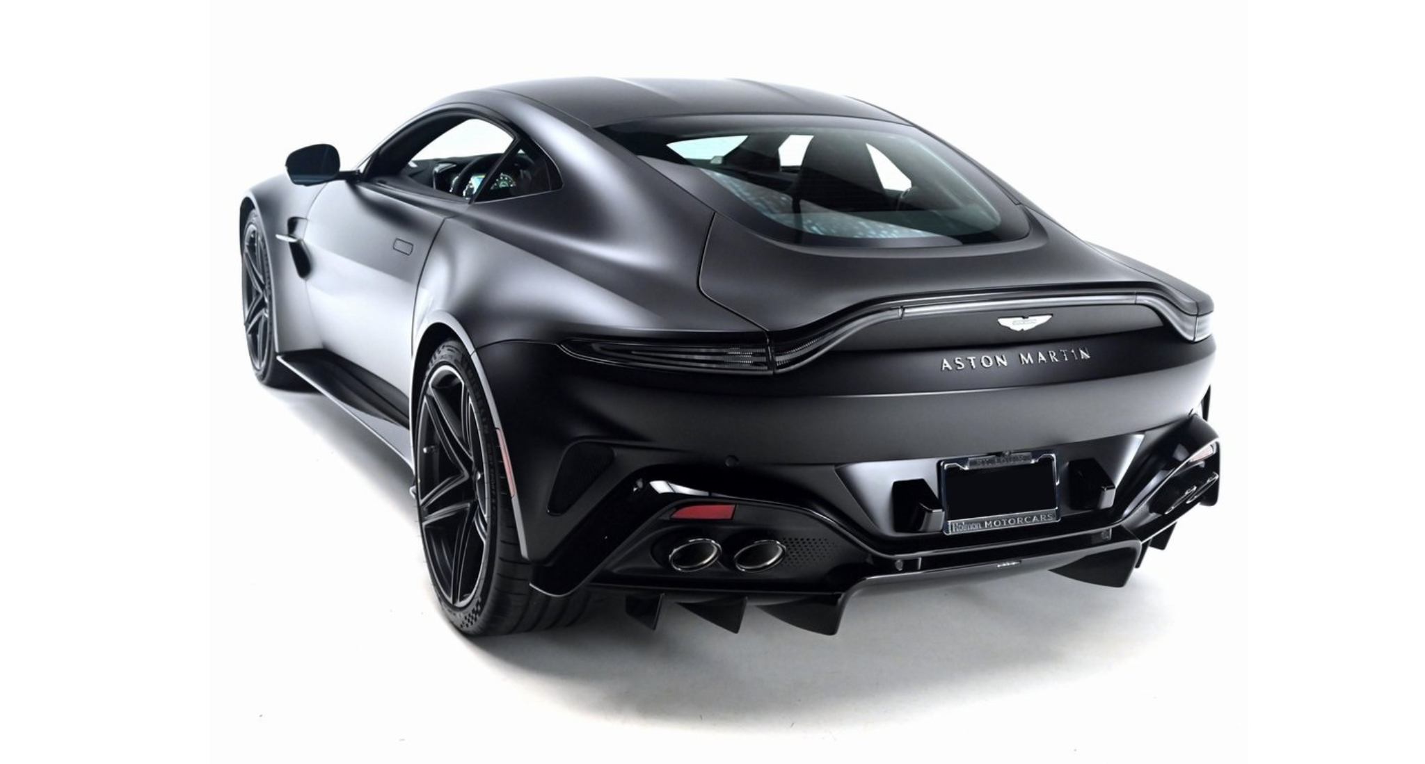 Rear profile of the 2025 Aston Martin Vantage Coupe in matte black with quad exhaust, LED taillights, and rear diffuser.